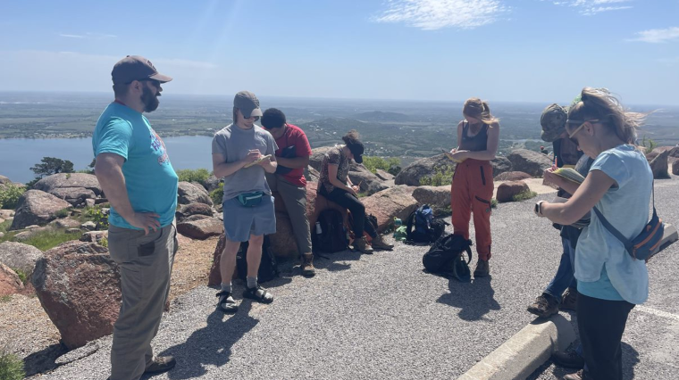 College students taking notes while outdoors on a scenic mountaintop