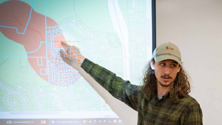 Student pointing out a GIS feature on a large screen.