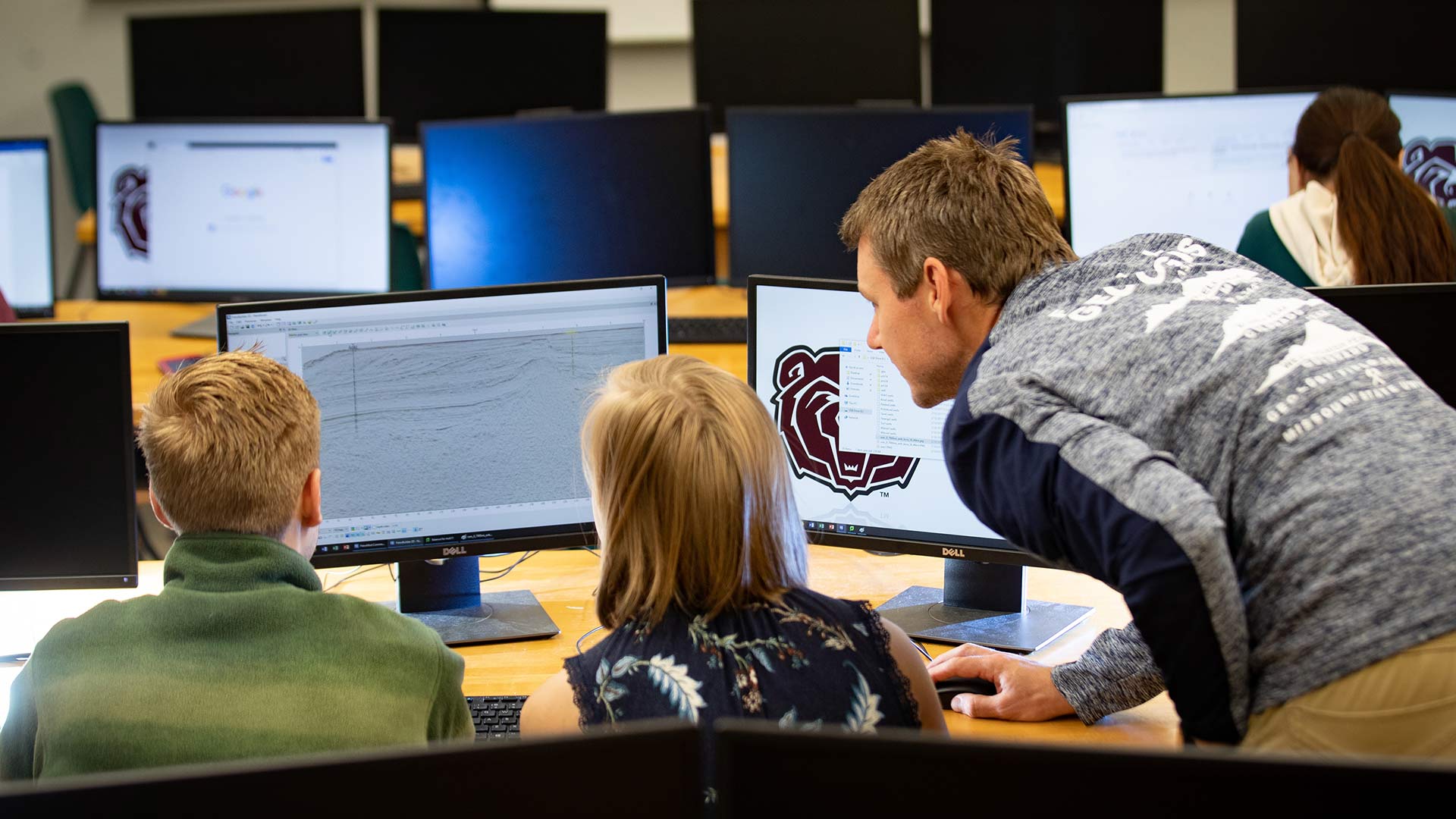 Students working with a faculty member in a computer lab.