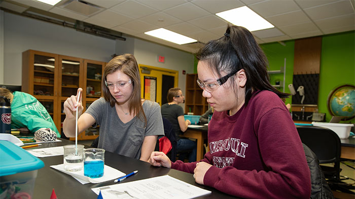 Two students working together with a class experiment