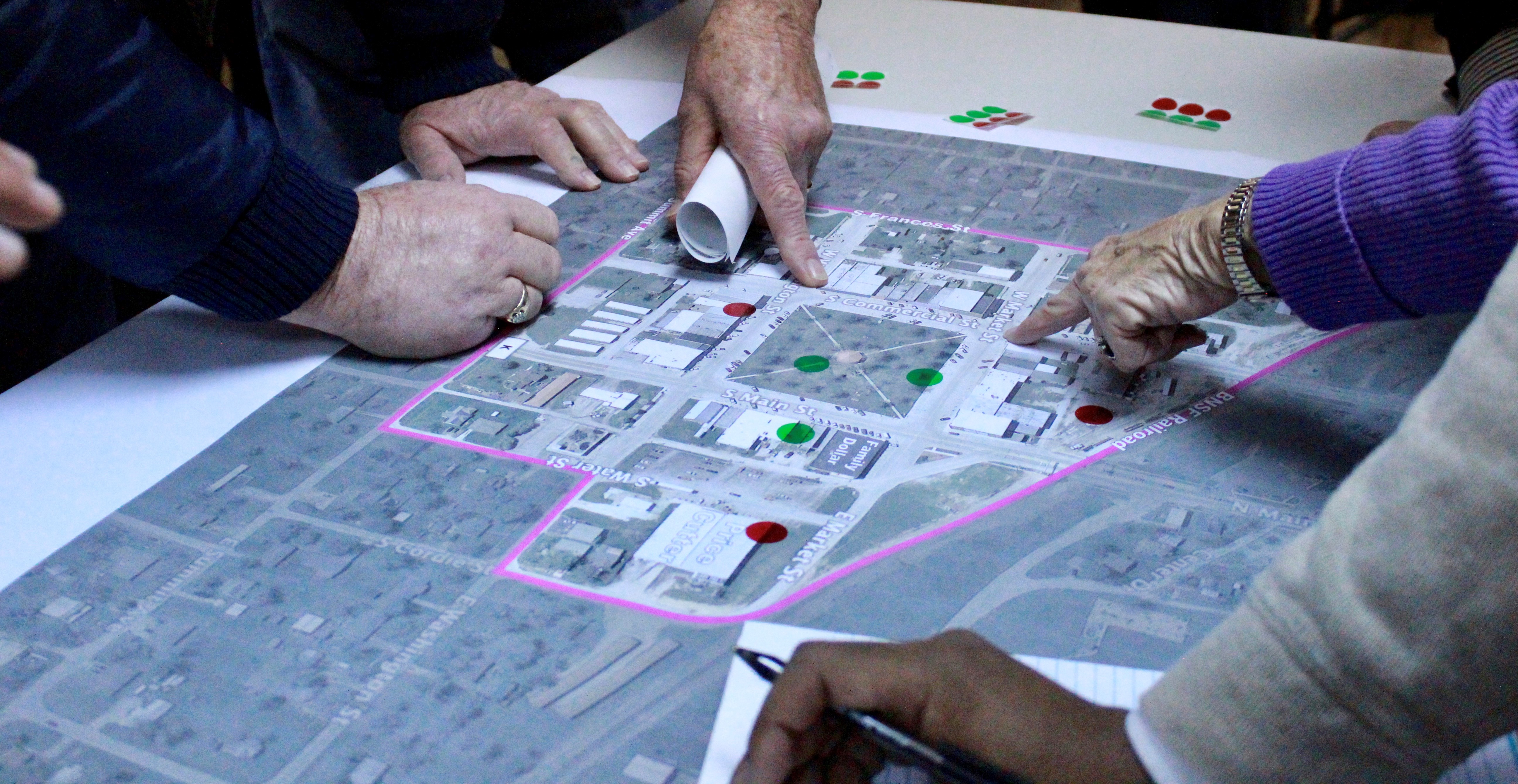 Large aerial map of a small community with people pointing at areas on the map.